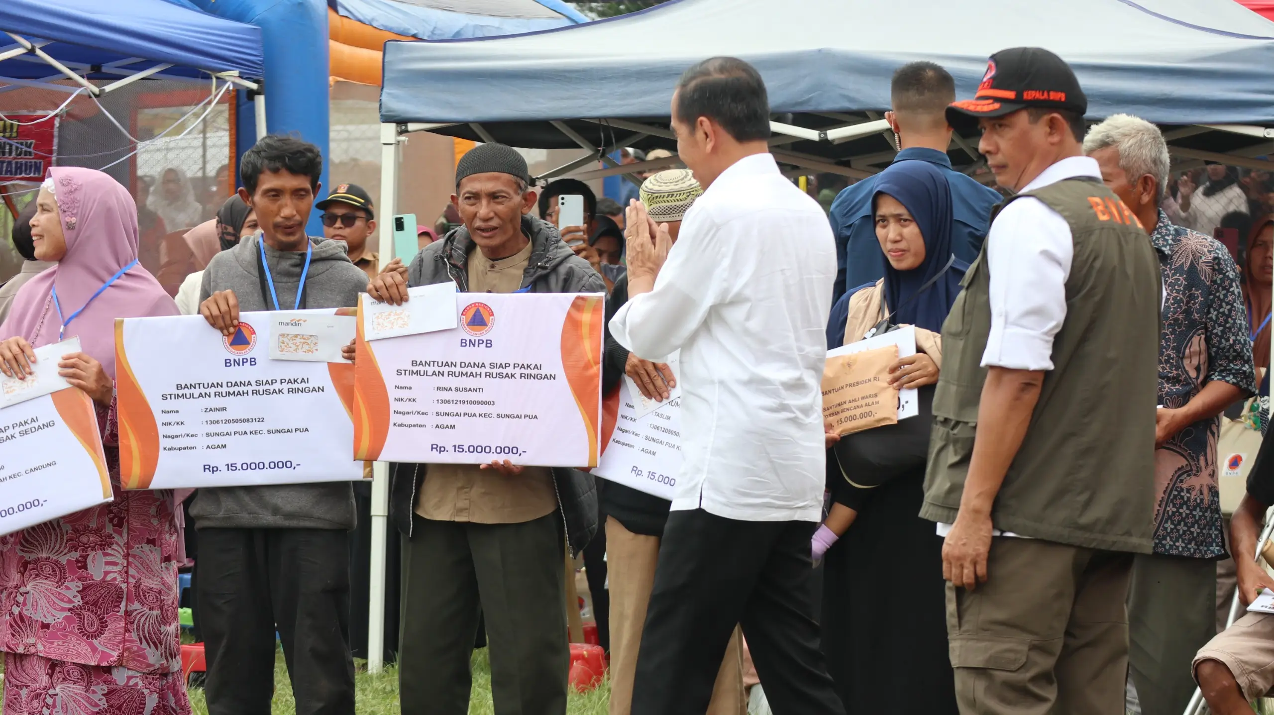 Kepala BNPB Letjen TNI Suharyanto, S.Sos., M.M., (rompi hijau dengan topi hitam) bersama Presiden Ir. Joko Widodo memberikan secara simbolis bantuan kepada masyarakat terdampak banjir lahar hujan Gunungapi Marapi di Pos Lapangan Batu Taba Kabupaten Agam, Sumatera Barat pada Selasa (21/5).